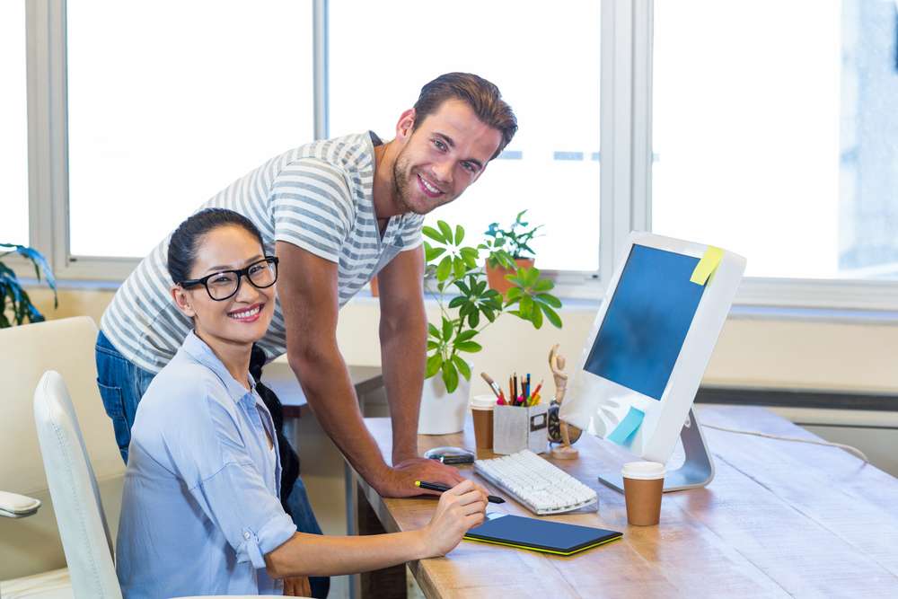 Smiling,partners,working,together,on,computer,in,the,office